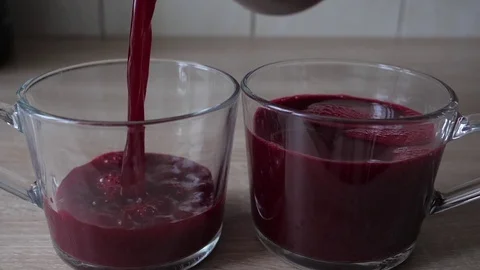 Pouring freshly made beetroot juice into glasses. Slow motion shot Stock Footage 82679301