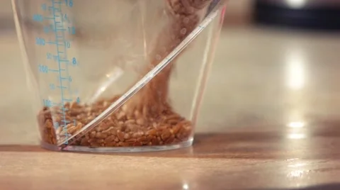 Pouring Grain into a Measuring Cup on a Kitchen Counter Stock Footage 52999380