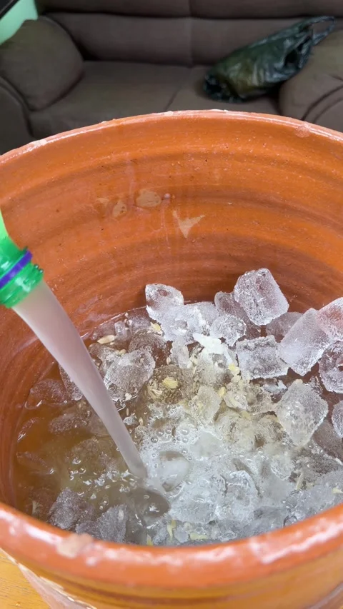 Pouring grapefruit soda into clay pitcher full of ice to make cantaritos Stock Footage 342351158