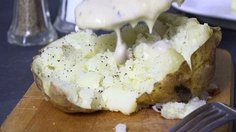 Pouring gravy on a potato Stock Footage 103444206