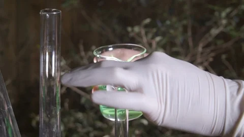 Pouring green liquid into a test tube in an outdoor environment at night Stock Footage 106938687