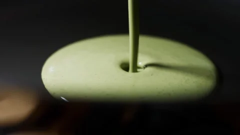 Pouring green pancake batter in a pan for cooking pancakes. Process of preparing Stock Footage 144904530