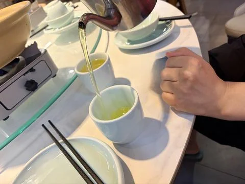 Pouring green tea into cups at a dining table. Stock-Fotos