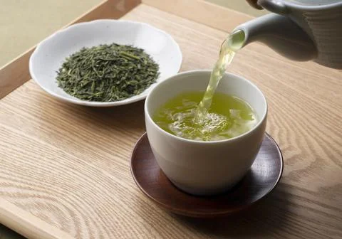 Pouring green tea into a teacup. Japanese green tea image Stock Photos