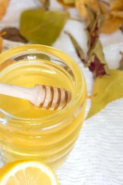 Pouring honey into jar on white table. Photos