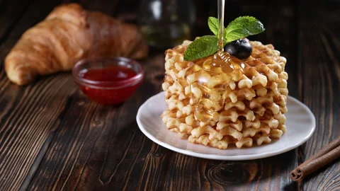 Pouring honey or syrup on a stack of freshly baked waffles decorated with Stock Footage 155605755