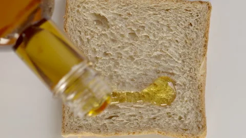 Pouring honey onto a piece of bread Stock Footage 253053434
