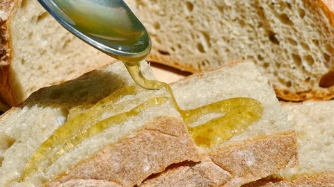 Pouring honey on a piece of bread, UHD Stock Footage 77544569