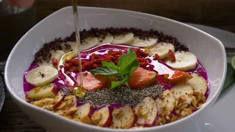 Pouring honey on smoothie bowl in Bali, healthy fruit breakfast Stock Footage