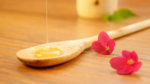 Pouring honey on a spoon. Composition with flowers (No 1) Stockbeeldmateriaal 66433413