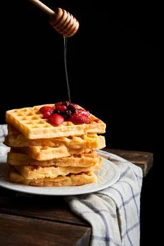 Pouring honey into a stack fresh waffles tower with berries. Copy space Stock Photos