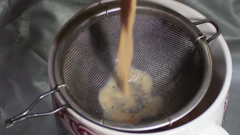Pouring hot black tea to cup through metal tea filter or tea strainer. Stock Footage 145338210