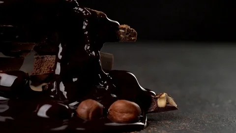 Pouring hot chocolate onto stack of various chocolate pieces and nuts in cocoa 스톡 동영상 78590883