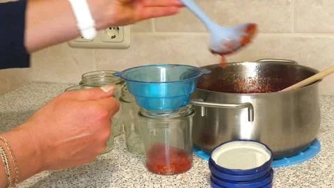 Pouring hot jam into sterilized jars using a funnel Stock Footage 318931015