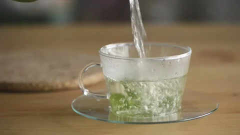Pouring hot mint tea into transparent glass tea cup. Stock Footage 161249759