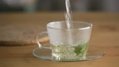 Pouring hot mint tea into transparent glass tea cup. Stock Footage 162239887