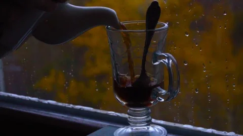 Pouring hot tea into a cup in front of the window in autumn. Close-up Stock Footage 100408627