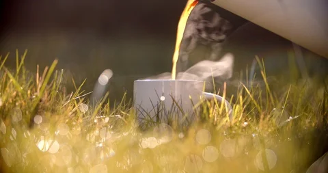 Pouring hot tea into a cup in the grass. Self-isolation in countryside. Stock Footage 128324381