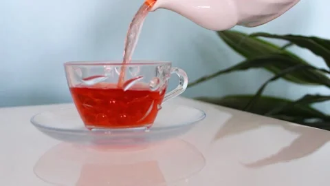 Pouring hot tea drom the pot into a glass cup Stock Footage 142164469