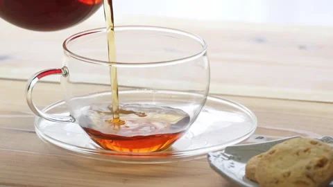 Pouring hot tea from a pot into a cup Stock Footage 274054385