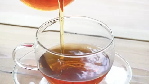 Pouring hot tea from a pot into a cup Stock Footage 274054386