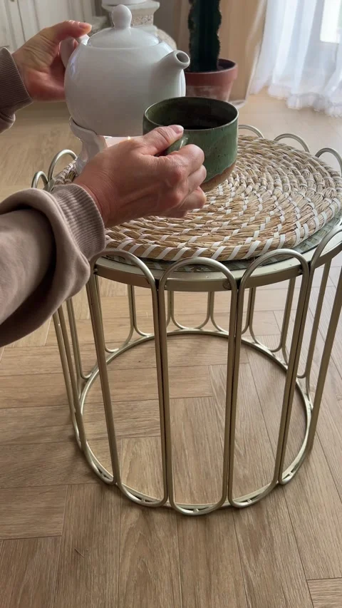 Pouring hot tea from teapot into mug and holding it in cozy home interior Stock Footage 345982194