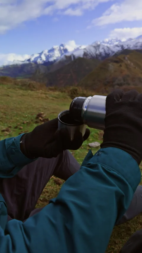Pouring hot tea from thermos during mountain hiking break. Video stock 337653191