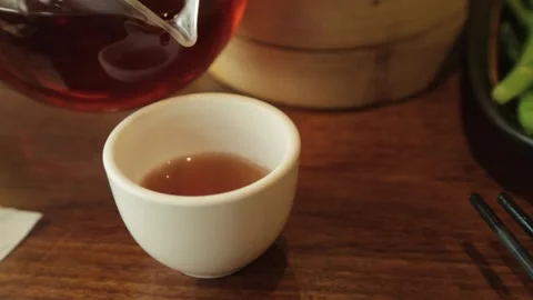 Pouring Hot Tea Into White Cup on Wooden Table in Beijing Restaurant Setting Stock Footage 345744856