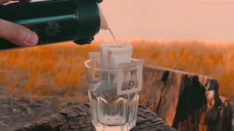 Pouring hot water from a kettle for drip coffee by the lake in morning Stock Footage 337420793