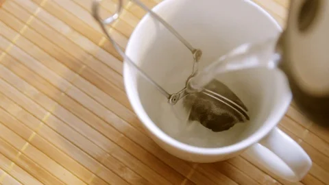 Pouring hot water on to a tea strainer Stock Footage 100820374