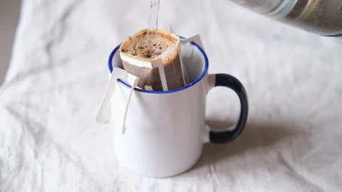 Pouring hot water through the paper coffee drip bag in mug or cup. Making Stock Footage 281140486