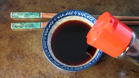 Pouring Iconic Red Soy Sauce bottle into Dish with Chopsticks for Sushi meal Vídeo Stock 126088029