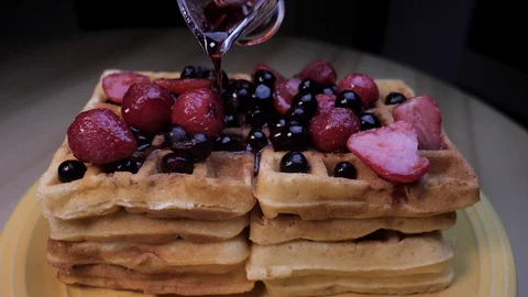 Pouring jam from sauser to waffles with srtawberries and blueberries closeup Stock Footage 129073549
