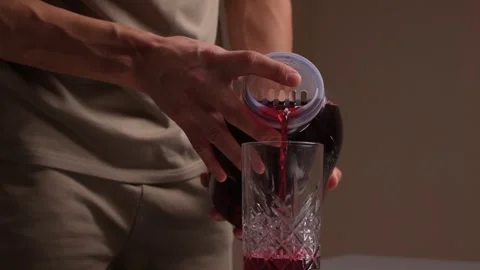 Pouring juice quickly. Closeup of hands pouring bright red juice into glass Stock Footage 346244252
