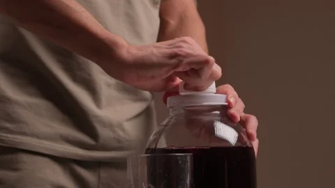 Pouring juice quickly. Closeup of hands pouring bright red juice into glass Stock Footage 346244255