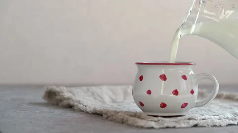 Pouring kefir into a dotted cup on a table, slow motion with copy space Stock Footage 172374313
