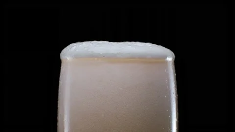 Pouring lager beer with bubbles and froth in glass over black background, Stock Footage 154739809