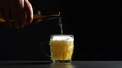 Pouring lager into a mug with black background Stock Footage 142149996