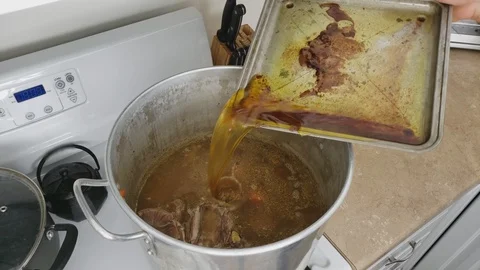 Pouring to large pot of hot broth all melted fat collected from roasted Duck Stock Footage 104250013