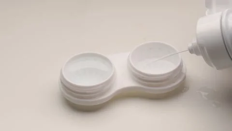 Pouring lens solution into a contact lens case Stock Footage 304682945