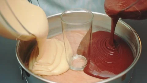 Pouring light and dark batter into metal mixing bowl indoors Stockbeeldmateriaal 342874772