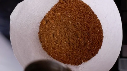 Pouring Light roasted ground coffee beans into paper filter for brewing Stock Footage 121847520