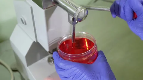 Pouring liquid collagen into a container. Laboratory procedure using red liquid. Stock Footage 304576748