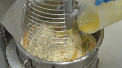 Pouring Liquid Egg Mixture into Flour in Industrial Dough Mixer. Adding Liquid Видео 333995227