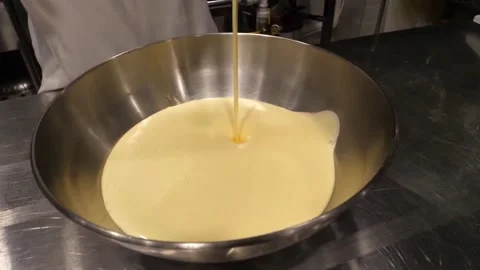 Pouring Liquid Egg Mixture into Large Metal Bowl in Commercial Kitchen 스톡 동영상 345291359