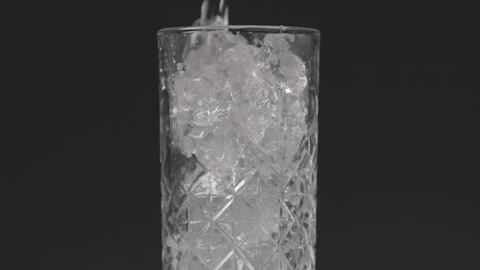 Pouring Liquid in Glas with Ice in Slow Motion Stock Footage 242157657