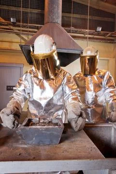 Pouring liquid gold into graphite casting form from furnace Stock Photos