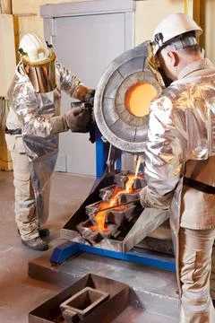 Pouring liquid gold into graphite casting form from furnace Stock Photos