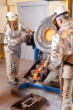 Pouring liquid gold into graphite casting form from furnace Stock Photos