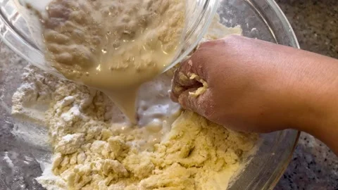 Pouring Liquid Mixture into Flour Dough in a Glass Bowl Stock Footage 345522330